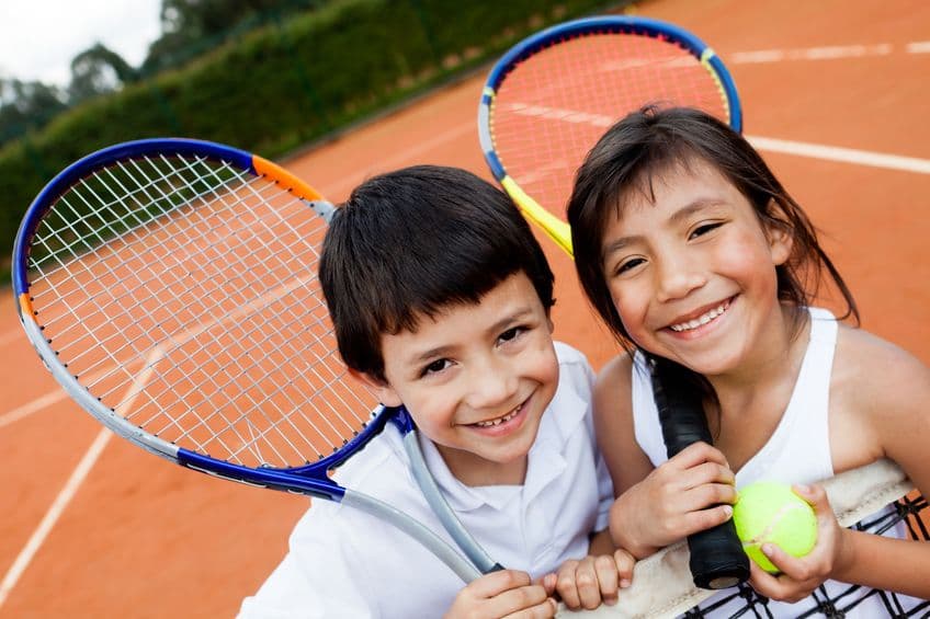 A tennis racket and ball on a clay court.